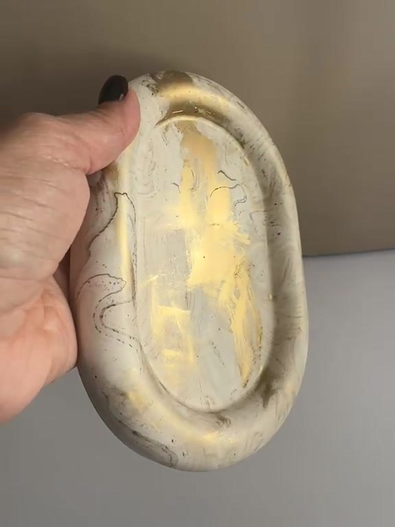 Finished oval dish with gold leaf, held in hand